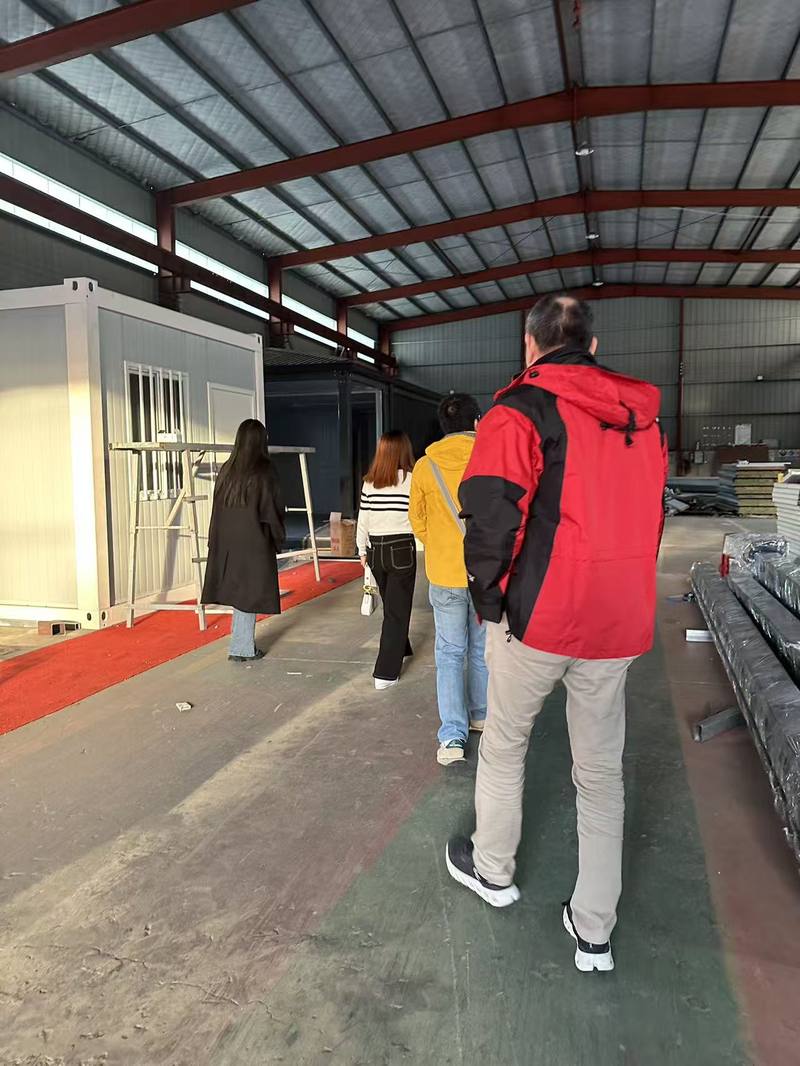 Group walking through the Taimao factory floor to inspect assembled container building modules
