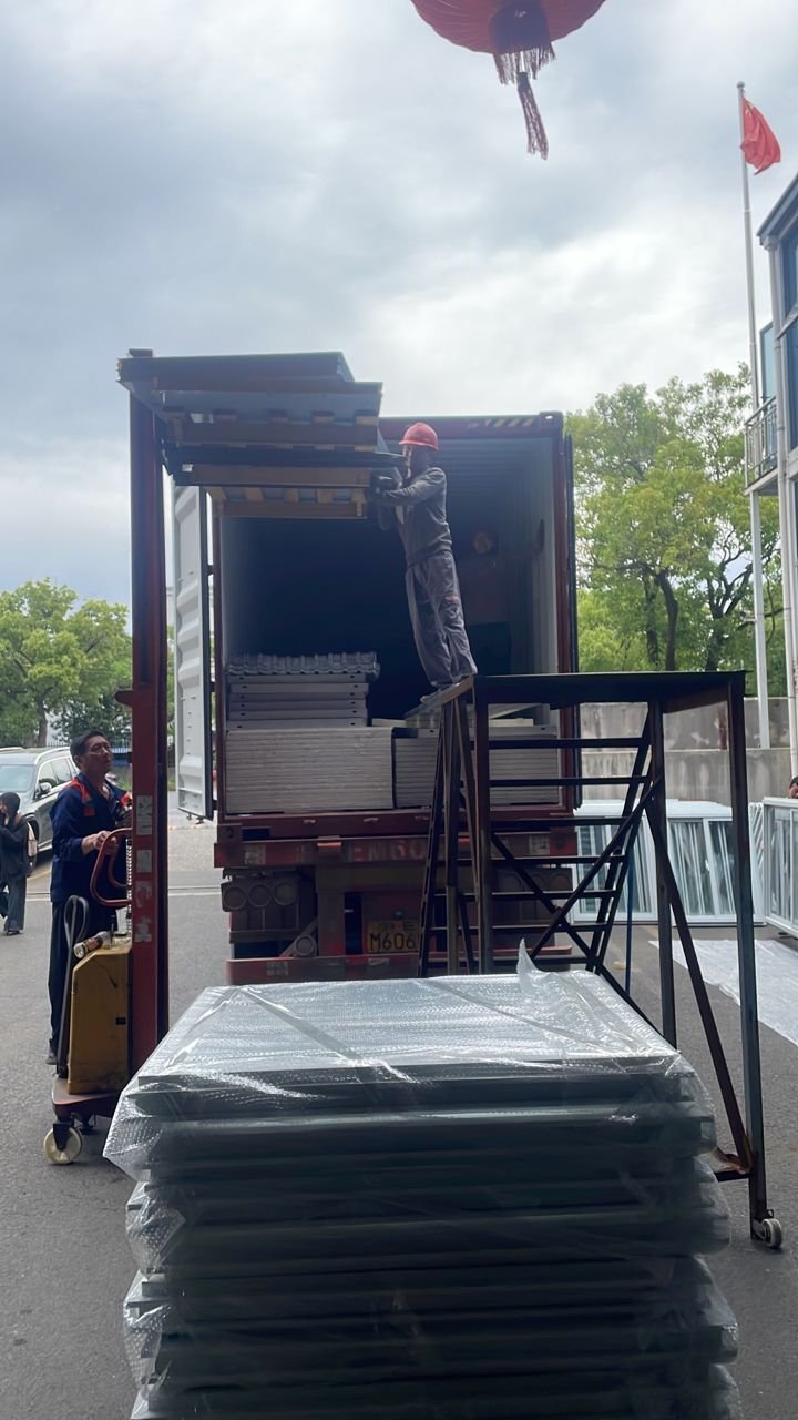 Worker guiding SIP panels into container during outdoor loading operation