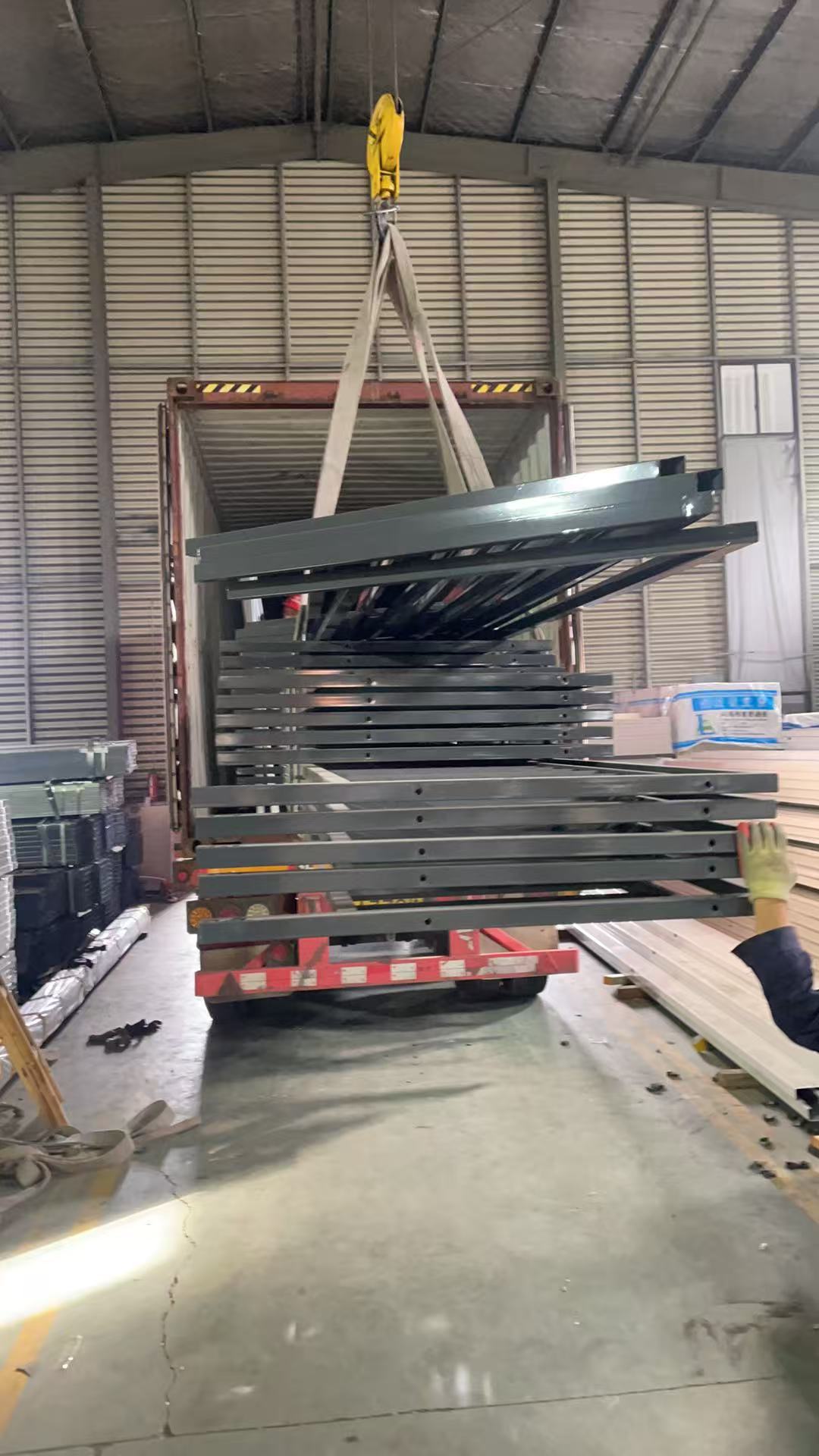 Steel frames being crane-lifted into the shipping container
