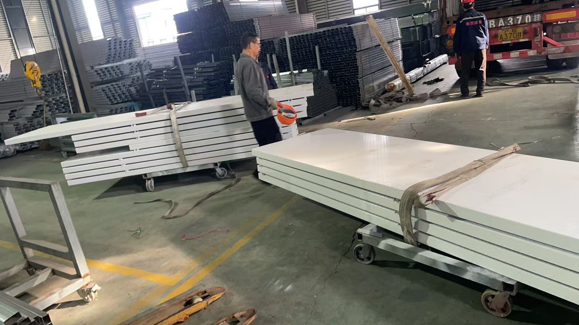 Factory floor with wall panels and steel sections on trolleys