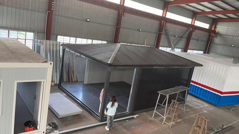 Wide-angle view of large modular building frame with distinctive folding pitched roof inside production hall