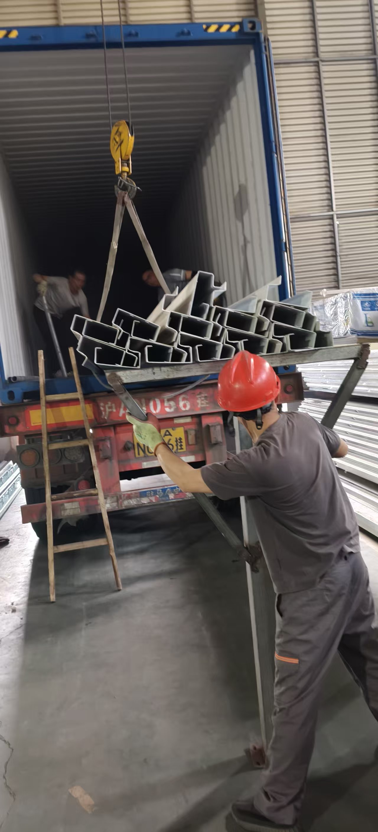 Workers loading aluminium profiles into shipping container
